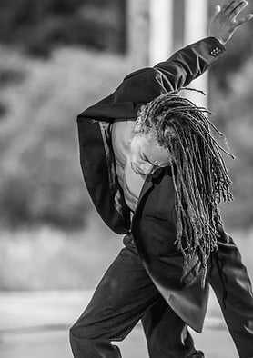 Contemporary dancer Amon Bey performing on stage in a black evening suit